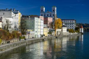 Der Innkai an Passaus Südseite führt direkt am Wasser entlang – vorbei an pastellfarbenen, mehrstöckigen Wohnhäusern und historischen Gebäuden