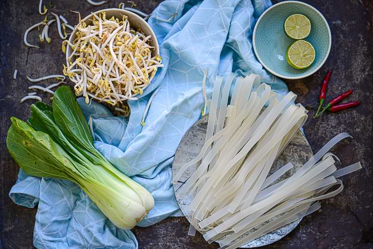 Einige Zutaten für das Pho-Rezept: breite Reisbandnudeln, Sojasprossen, Pak Choi, Limetten und – wer will –Chili